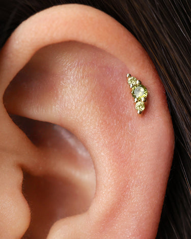 Peridot climber flat back earrings in 18k gold as helix earrings on model.