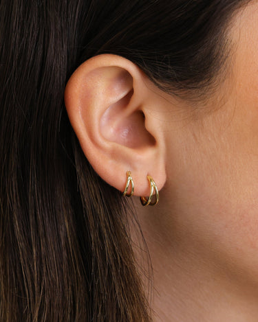 Solid double clicker hoop earrings in 18K gold and sterling silver on model. 